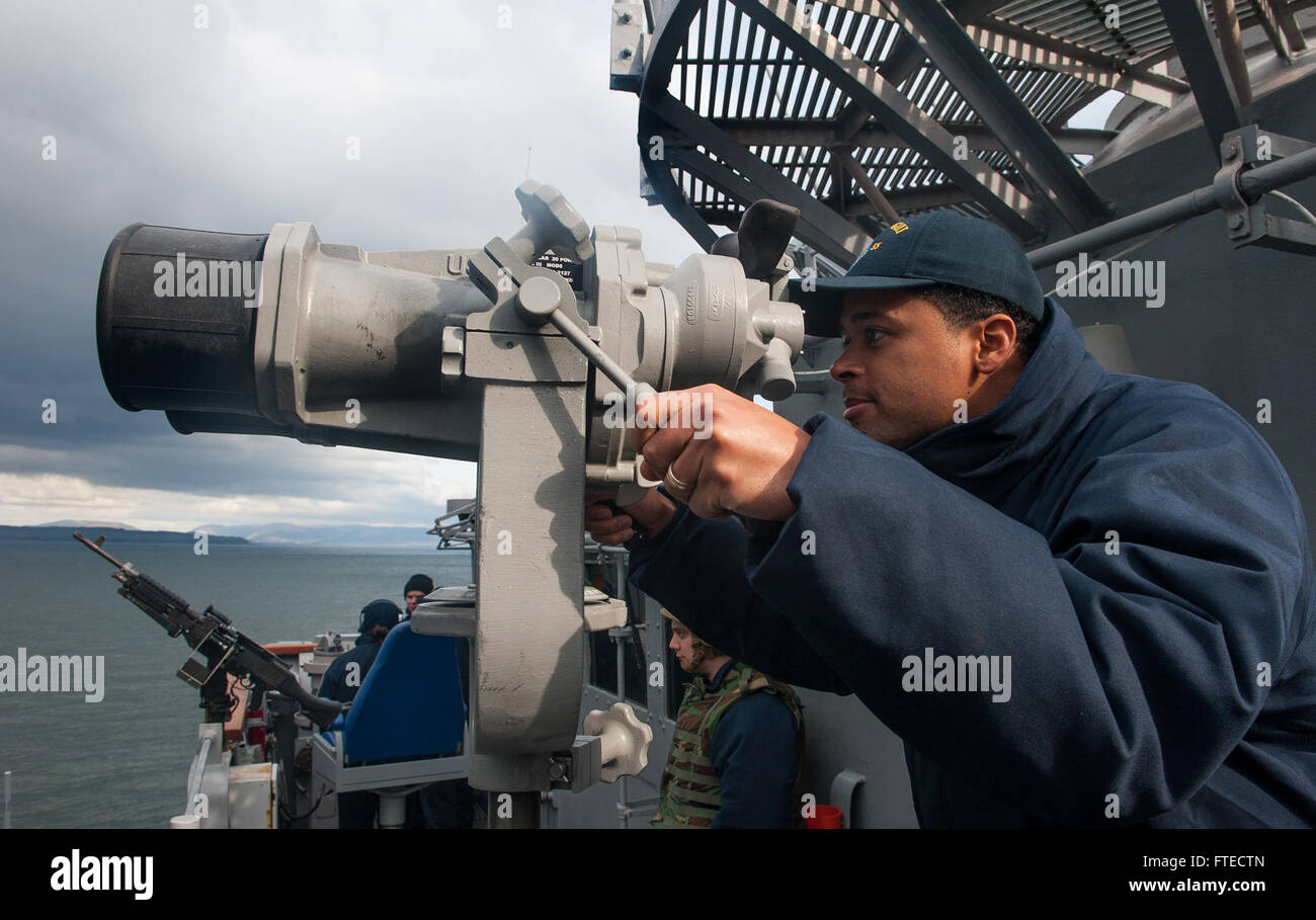 Il 28 marzo 2014, il tenente Jason Jeanpierre a bordo della USS Leyte Gulf (CG 55) guarda attraverso l'ottica della nave mentre era in viaggio verso Faslane, in Scozia, per l'esercitazione NATO Joint Warrior 14-1, che migliora le capacità multi-belliche tra le marine alleate. Foto Stock