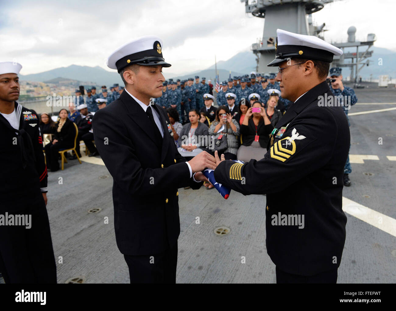 Maximo Caimaires-Vega, capo della nave, riceve una bandiera durante la cerimonia di ritiro a bordo della USS Mount Whitney (LCC 20) a Gaeta, in Italia. La USS Mount Whitney, schierata in avanti a Gaeta, serve come nave di comando e controllo per la sesta flotta statunitense in Europa. Foto Stock
