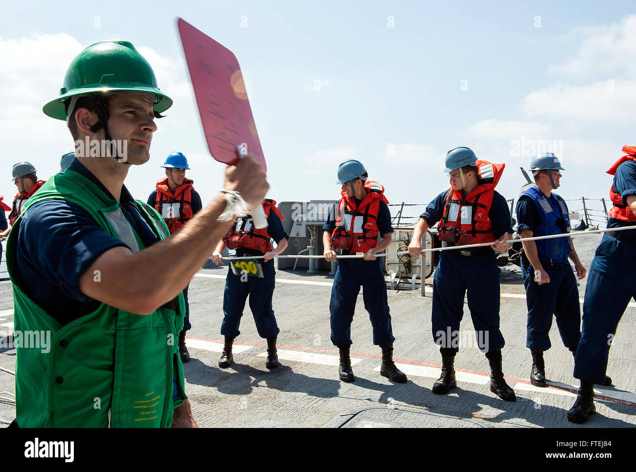 Mare Mediterraneo (Agosto 18, 2013) Ð Cryptologic tecnico (tecnico) 2a classe Benjamin Kieldhold, da Sioux City, Iowa, segnali per ricevere la linea durante un rifornimento verticale in mare (VERTREP) con militare Sealift oliatore comando USNS Leroy Grumman (T-AO 195) a bordo del missile destroyer USS gravemente (DDG 107). Gravemente, homeported a Norfolk, Virginia, è su una distribuzione programmata sostenere le operazioni di sicurezza marittima e di teatro la cooperazione in materia di sicurezza gli sforzi nella sesta flotta area di responsabilità. Foto Stock