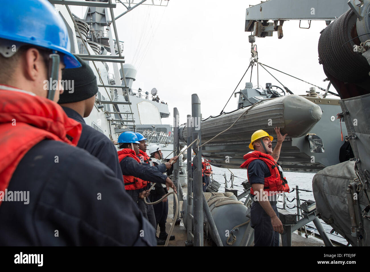 Mare Mediterraneo (nov. 15, 2014) - di Boatswain Mate 2a classe Alan Farthing, da Grove City, Ohio, dà istruzioni ai gestori di linea come egli controlla un rilievo-gonfiabile dello scafo della barca entrobordo swing durante una barca di operazione di recupero a bordo della USS Cole (DDG 67). Cole, un Arleigh Burke-class guidato-missile destroyer homeported in Norfolk, sta conducendo operazioni navali negli Stati Uniti Sesta flotta area di operazioni a sostegno degli Stati Uniti per gli interessi di sicurezza nazionali in Europa. Foto Stock