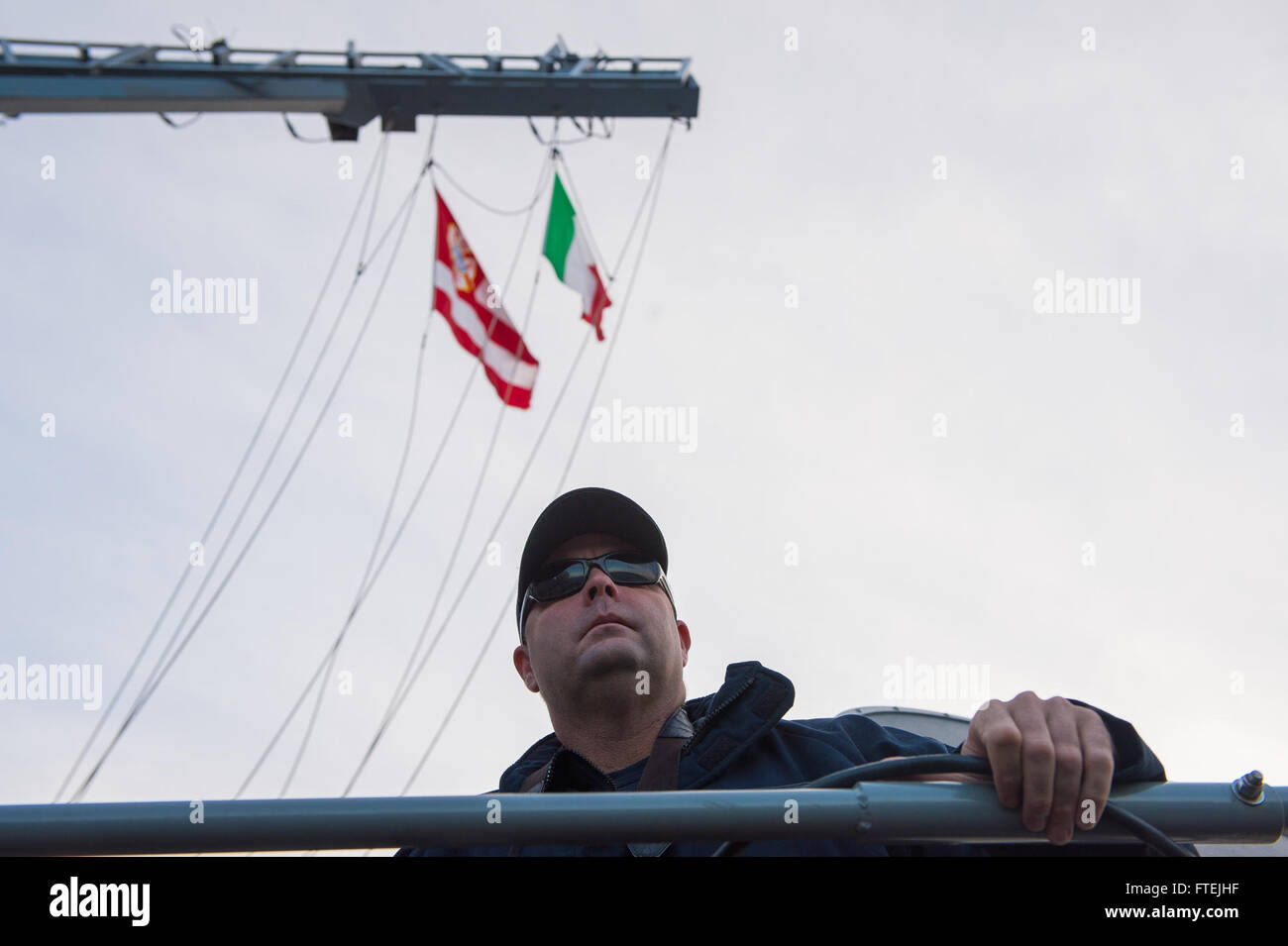 AUGUSTA BAY, Sicilia (dec. n. 8, 2014) della Cmdr. Dennis Farrell, comandante, USS Cole (DDG 67), sorge sul ponte come la nave tira a Augusta Bay, Sicilia, durante una prevista visita porta 8 dicembre 2014. Cole, un Arleigh Burke-class guidato-missile distruttore, homeported in Norfolk, sta conducendo operazioni navali negli Stati Uniti Sesta flotta area di operazioni a sostegno degli Stati Uniti per gli interessi di sicurezza nazionali in Europa. Foto Stock