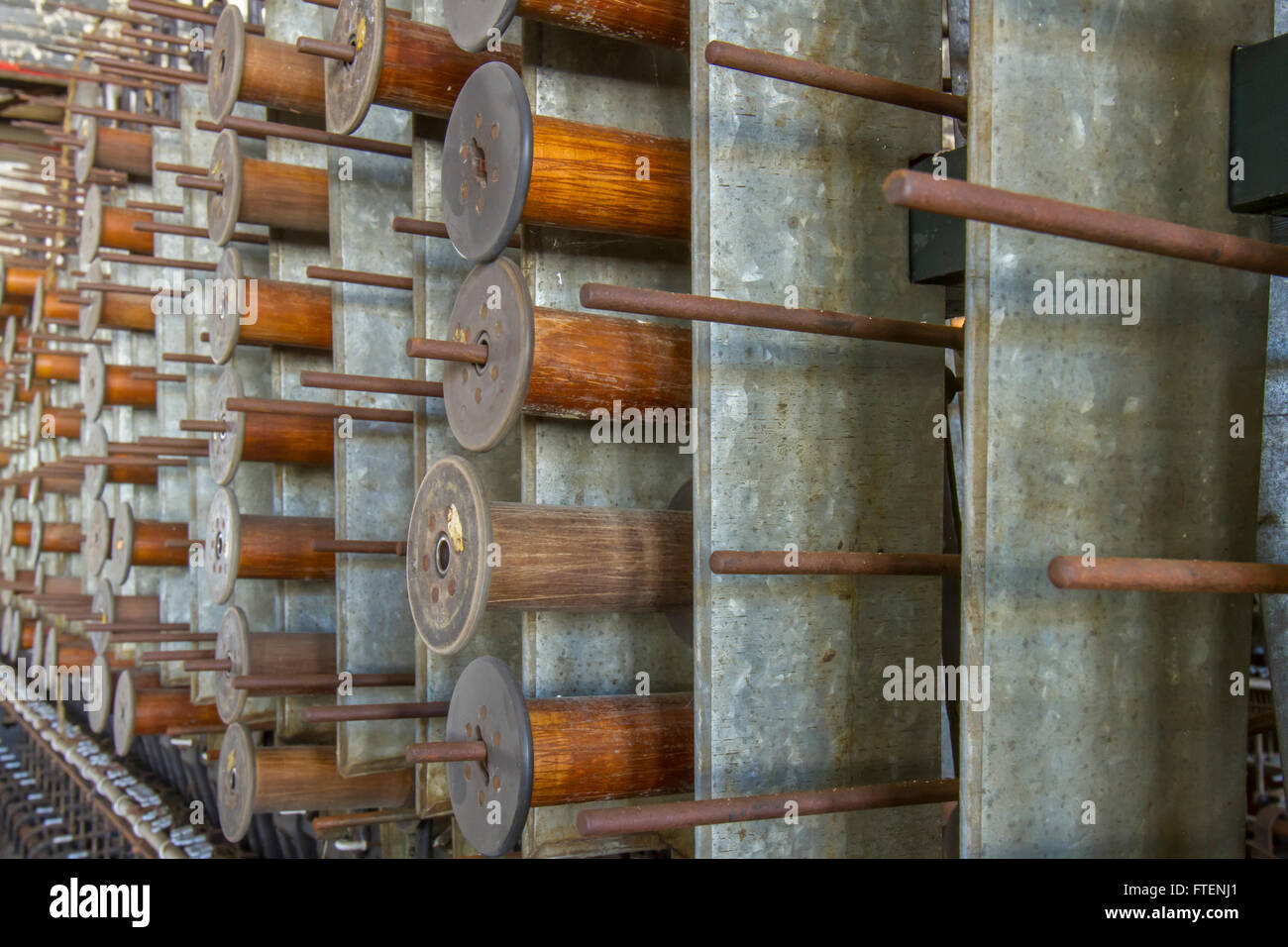 Bobine in legno appeso su pioli di antiche apparecchiature nel giro di un secolo la seta gettando fabbrica. Foto Stock