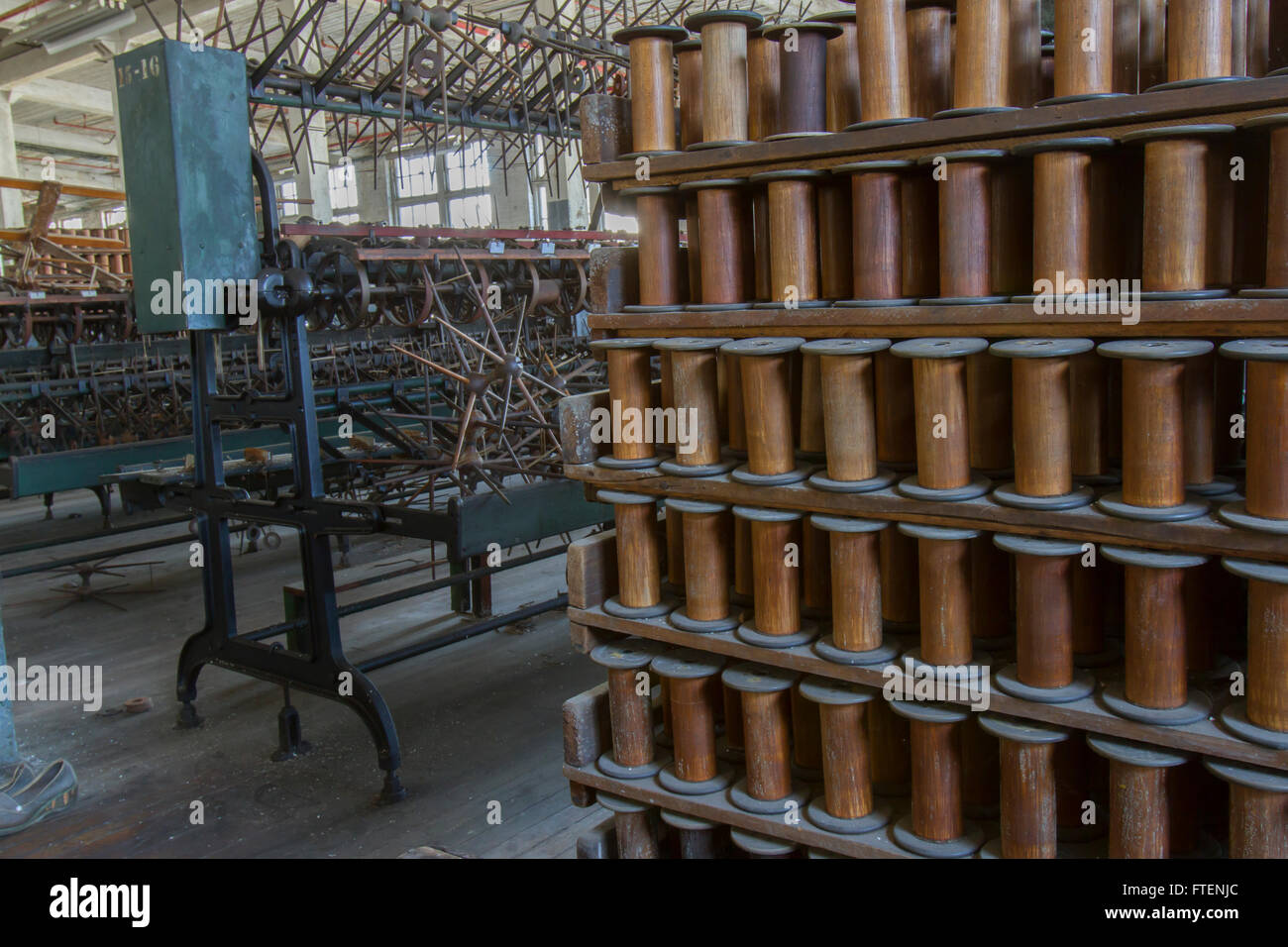 Rack di bobine in legno con antiche attrezzature sul pavimento della fine del secolo la seta gettando fabbrica. Foto Stock