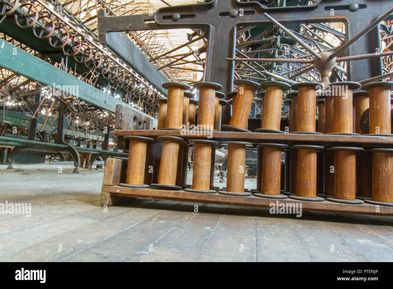 Bobine in legno accanto alle antiche attrezzature in giro del secolo la seta gettando fabbrica. Foto Stock