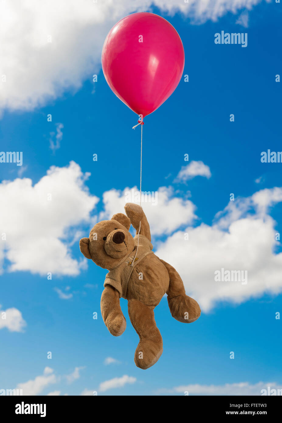 Vista frontale di un orso di peluche appeso ad un palloncino per la sua zampata Foto Stock