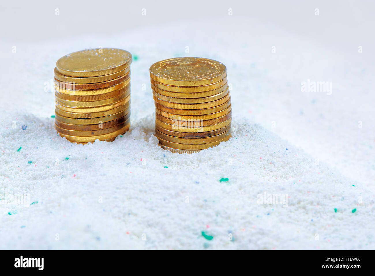 Risparmio di denaro sulla qualità conveniente il detersivo in polvere, monete impilate in detergenti per bucato. Foto Stock
