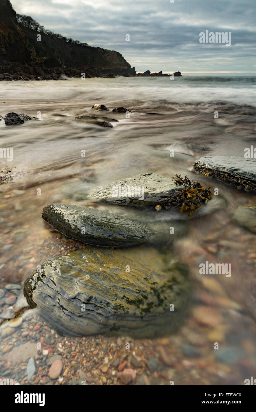 Lee Bay Beach, Devon, Inghilterra, rivela splendide rocce e ciottoli come il mare si ritira con la bassa marea. Foto Stock