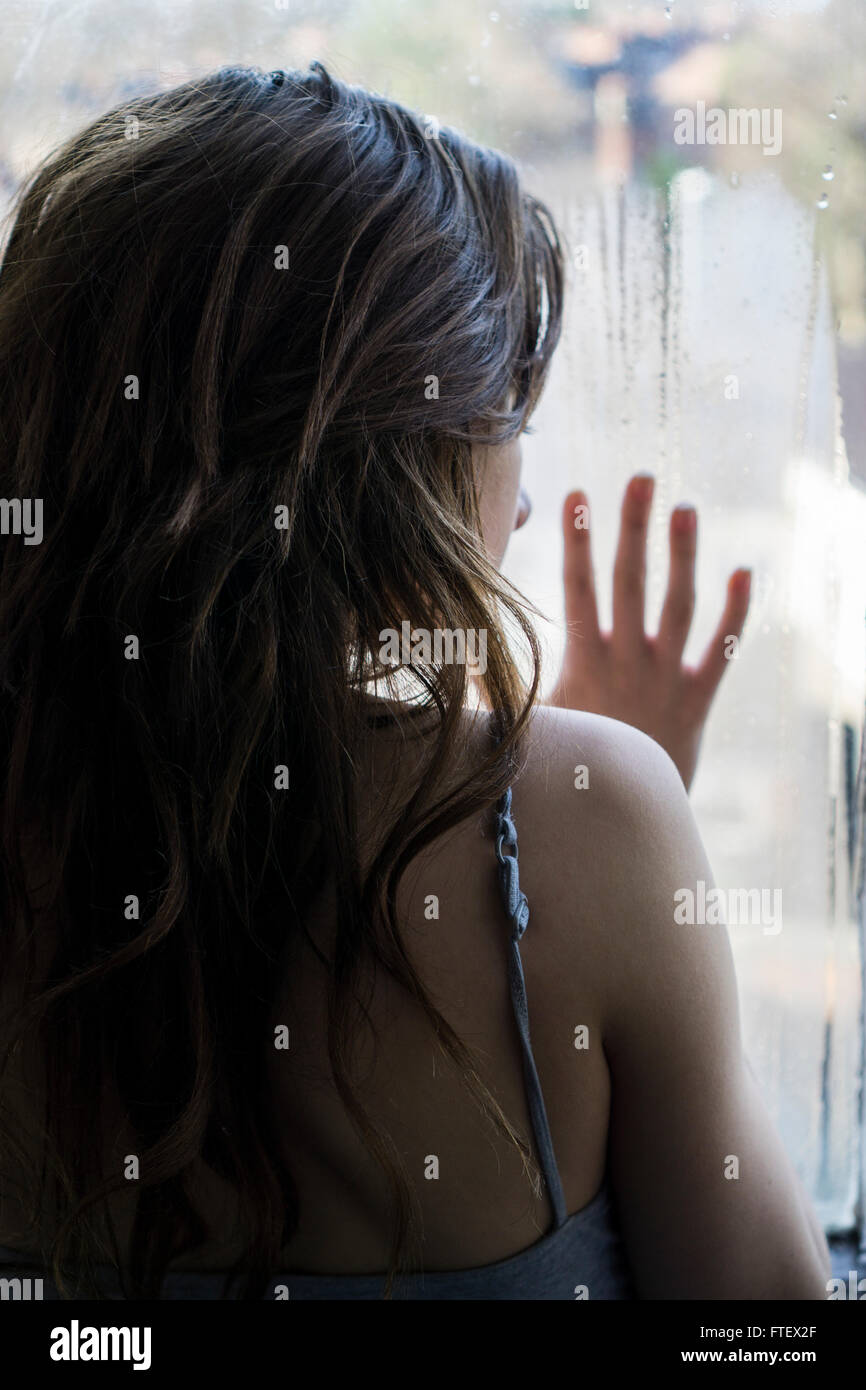 Vista posteriore di una giovane donna mano contro la finestra Foto Stock