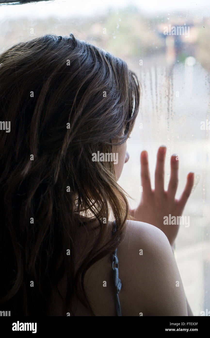 Vista posteriore di una giovane donna mano contro la finestra Foto Stock