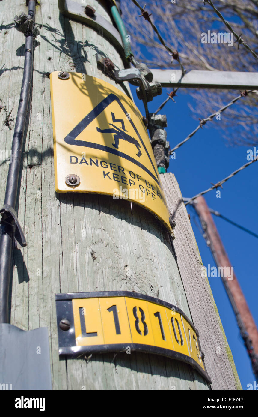 In legno palo del telegrafo uk,con cartelli di avvertimento pericolo di morte in alta tensione Foto Stock