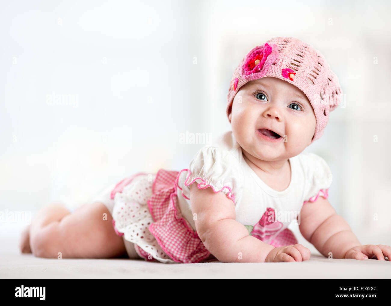 Piuttosto sorridente bambina giacente su stomaco e guardando in alto Foto Stock