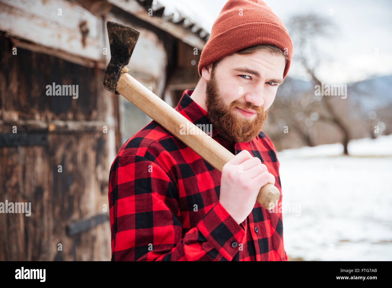 Sorridente uomo barbuto in camicia a scacchi e hat holding ax Foto Stock