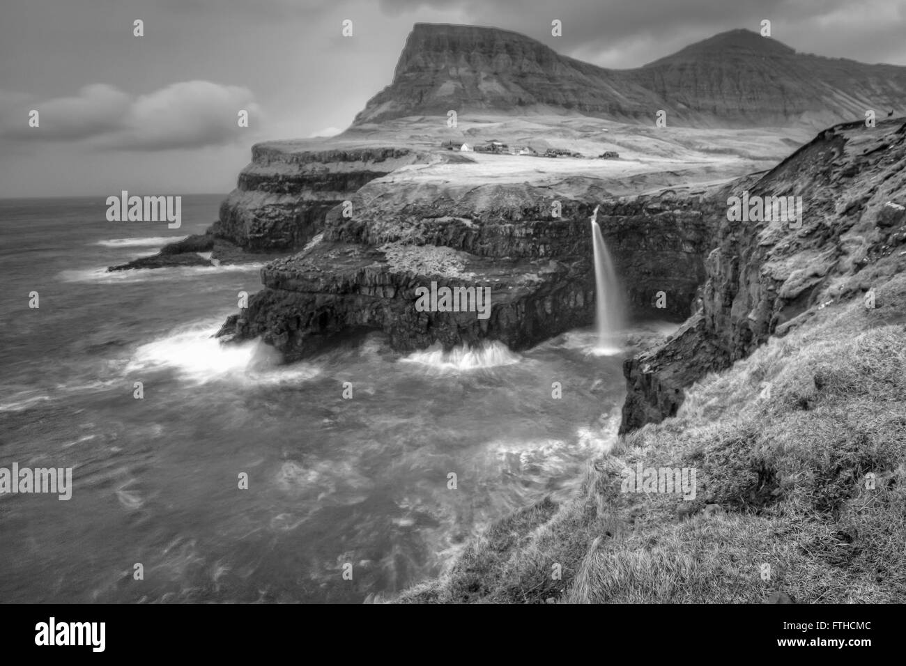 Gasadalur villaggio e la sua leggendaria cascata, funzionario ministeriale, Isole Faerøer, Danimarca. Lunga esposizione. In bianco e nero. Foto Stock