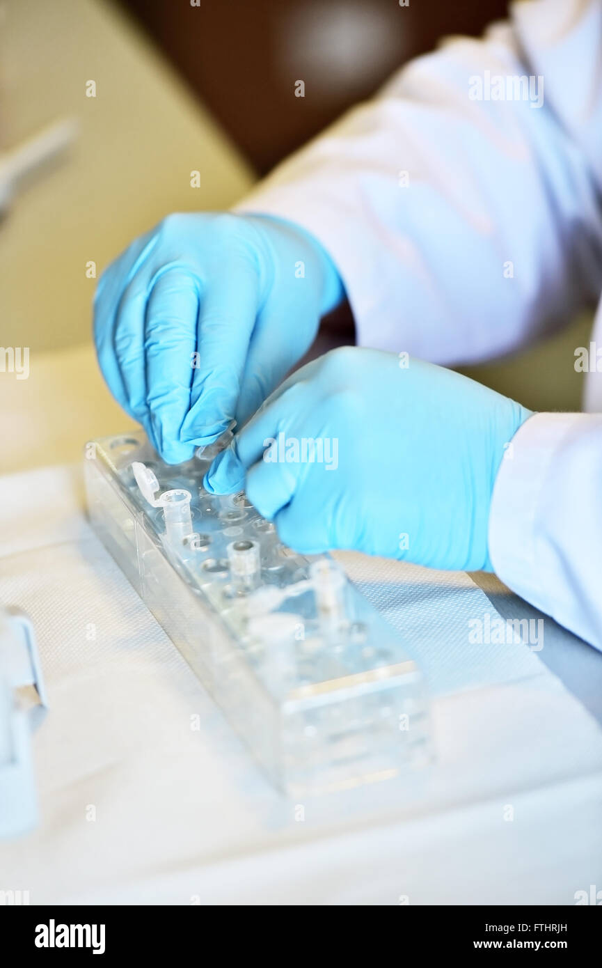 Dettaglio con il ricercatore mani lavorando con contagocce medica e i tubi in un laboratorio di eseguire un test del DNA Foto Stock