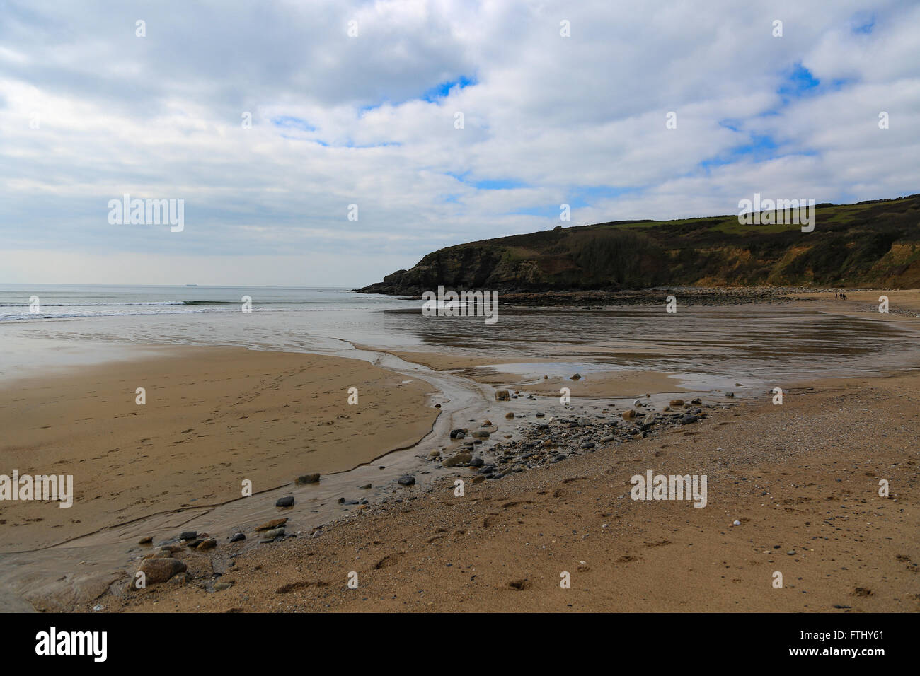 Splendide calette vicino la lucertola Cornwall, fiume che scorre verso il mare, scogliere, pietre, cielo blu e nuvole, Foto Stock