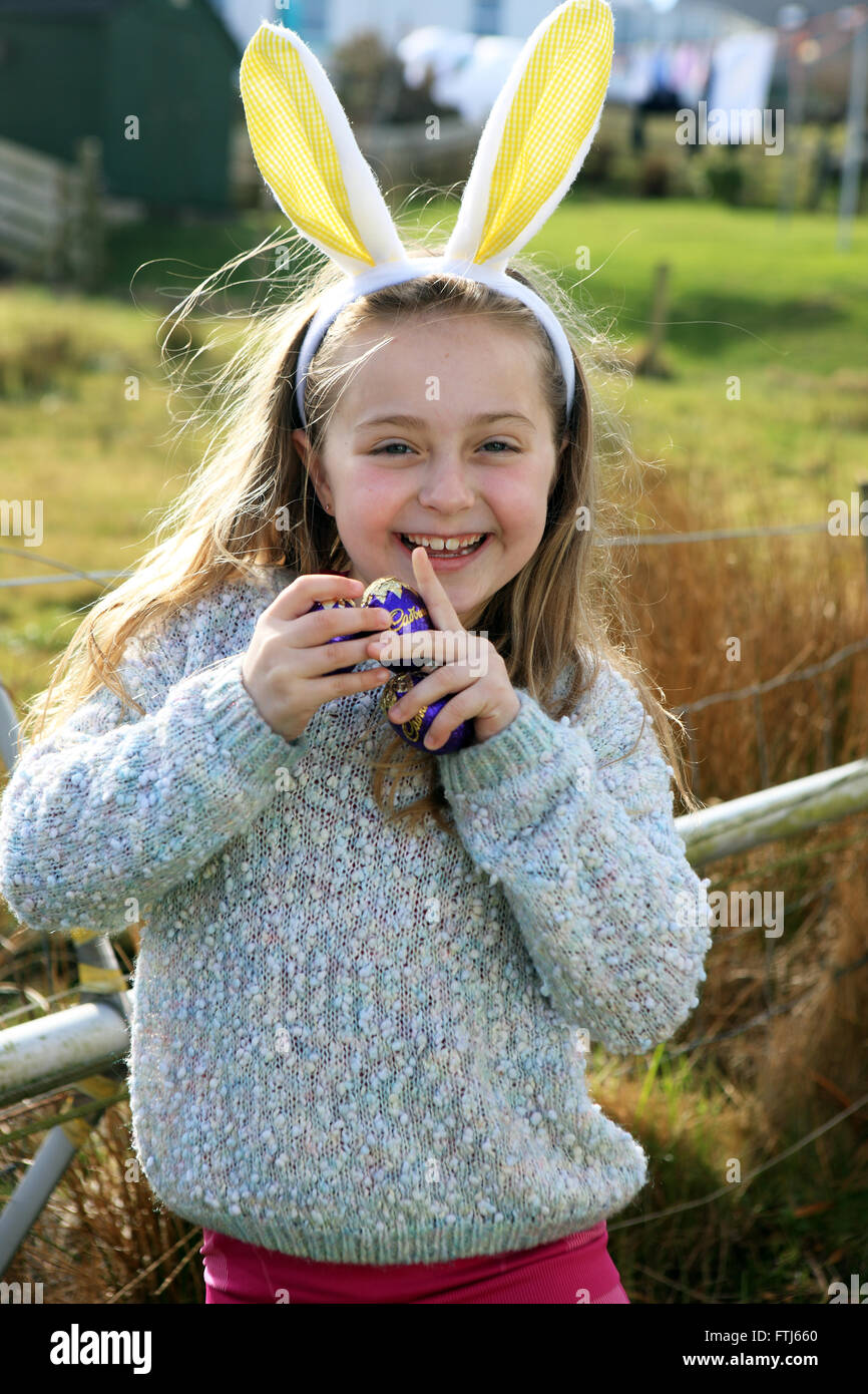 Orecchie di coniglietto su sette anno vecchia ragazza mentre su un uovo di pasqua caccia Foto Stock