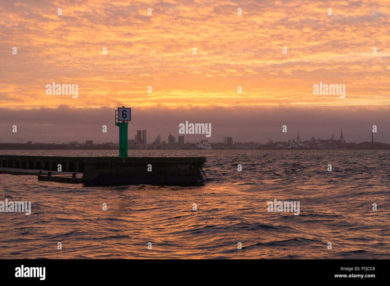 Il molo sul mare e la città di Tallinn silhouette sul tramonto, onde colorate movimento nella parte anteriore Foto Stock