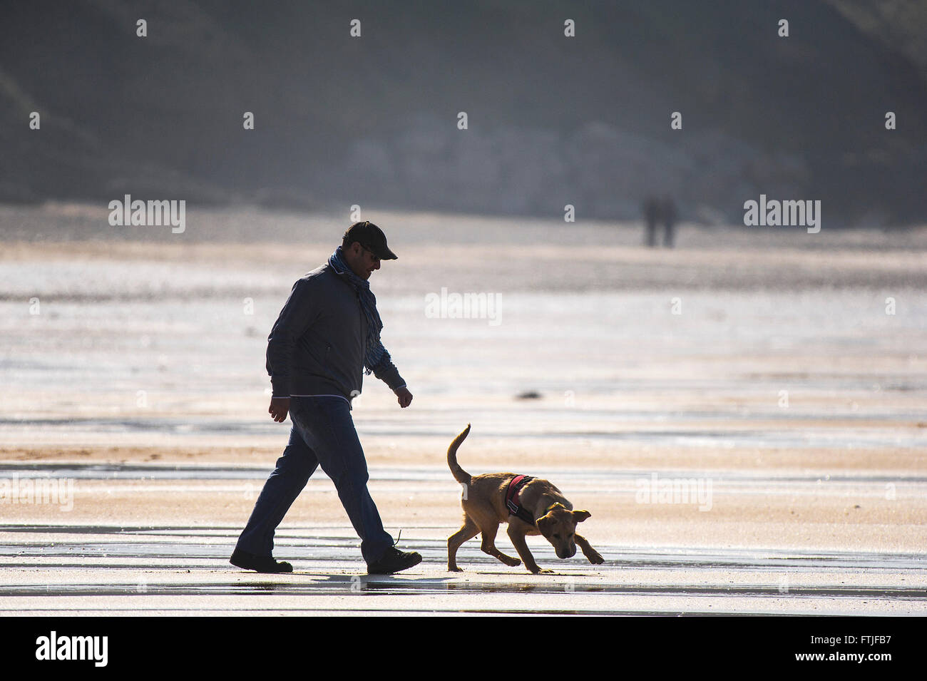 Un uomo e il suo cane che godono di una buona passeggiata sulla Fistral Beach in Newquay, Cornwall. Foto Stock