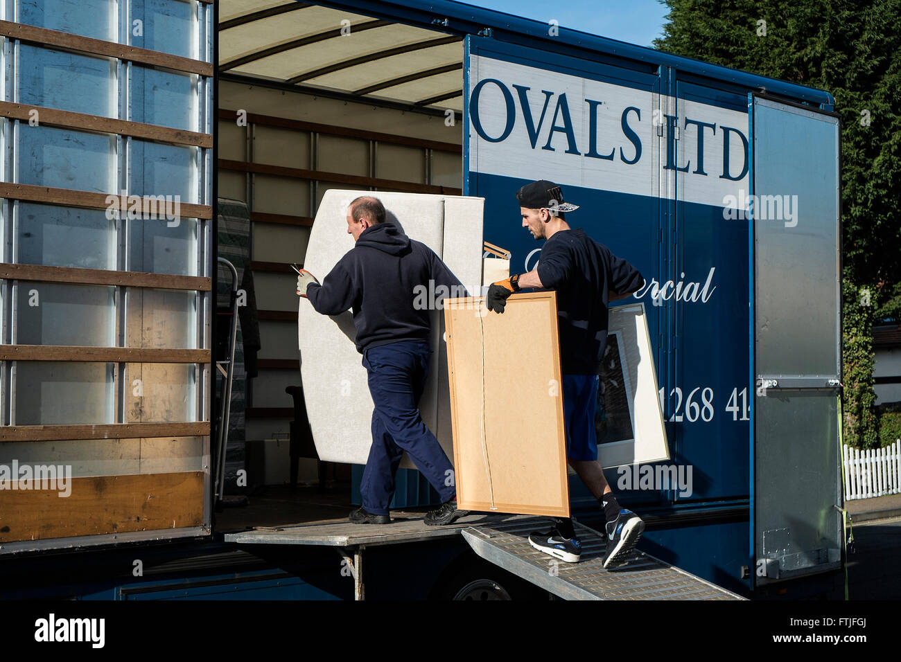 Distacco degli uomini il caricamento degli articoli per la casa in un mobili rimozione van. Foto Stock