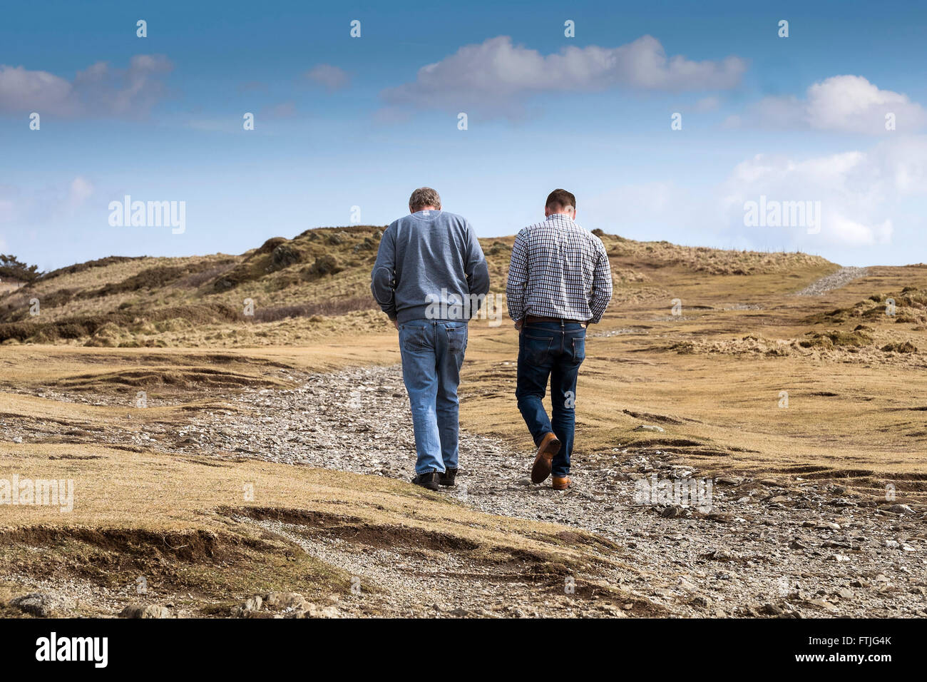 Un padre e figlio in una profonda conversazione attraversando a piedi il Warren su Pentire est in operazioni automatiche di fine campo, Newquay Cornwall. Foto Stock