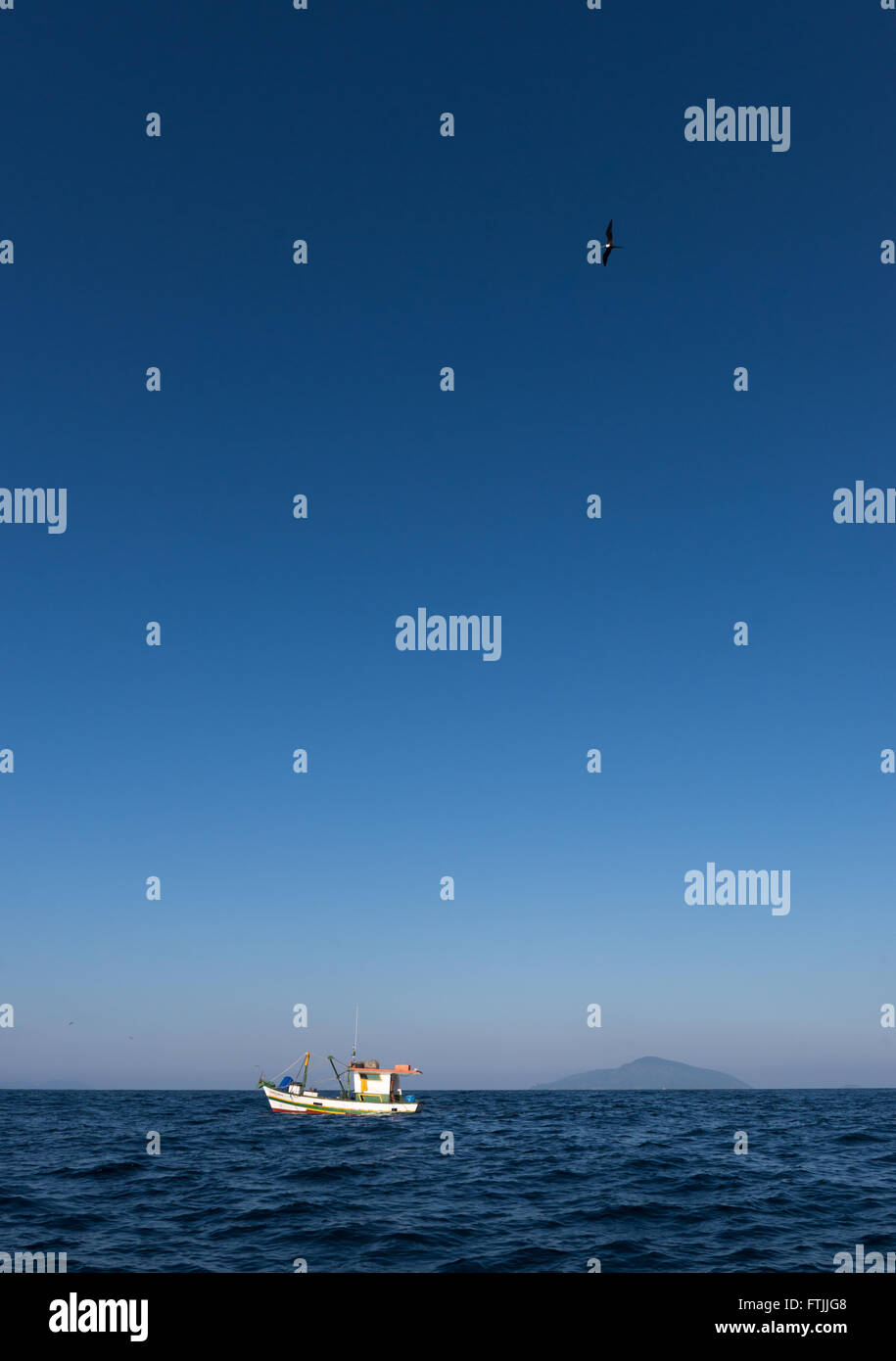Una barca da pesca trascinando un gambero net off Ilhabela, se il Brasile. Uccelli come sule e frigatebirds sono i seguenti per ottenere il rottame Foto Stock