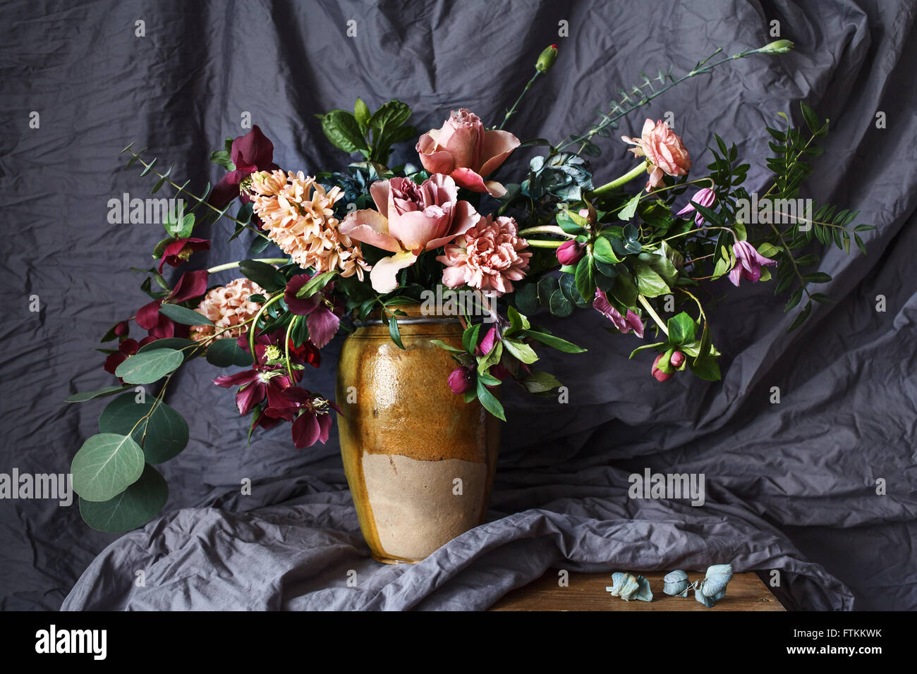 Fiore nel vaso sul tavolo sullo sfondo di tessuto grigio Foto Stock