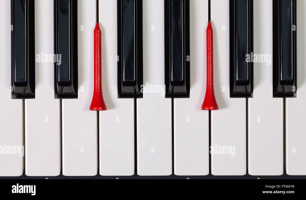 Virtuosi di gioco - Una tastiera di pianoforte e differenti palline da golf e tee di legno Foto Stock