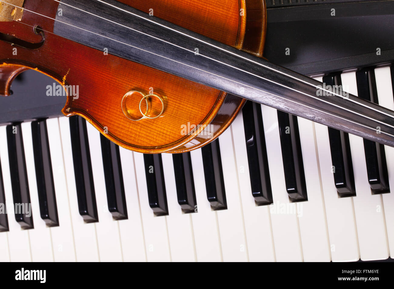 Dettaglio della tastiera di pianoforte, vecchio violino e gli anelli di nozze Foto Stock