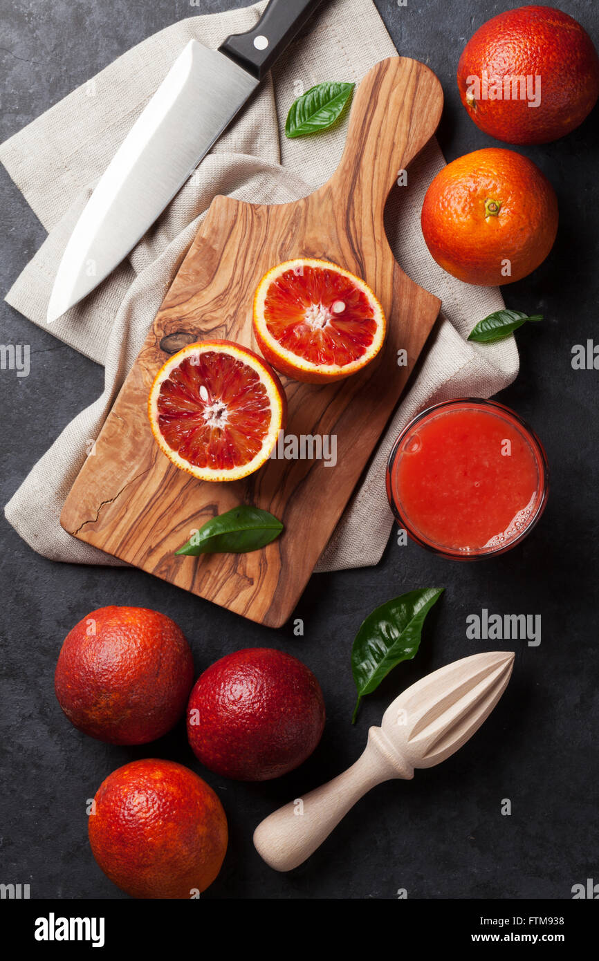 Agrumi freschi e rosso succo di arancia in pietra scura sullo sfondo. Vista superiore Foto Stock