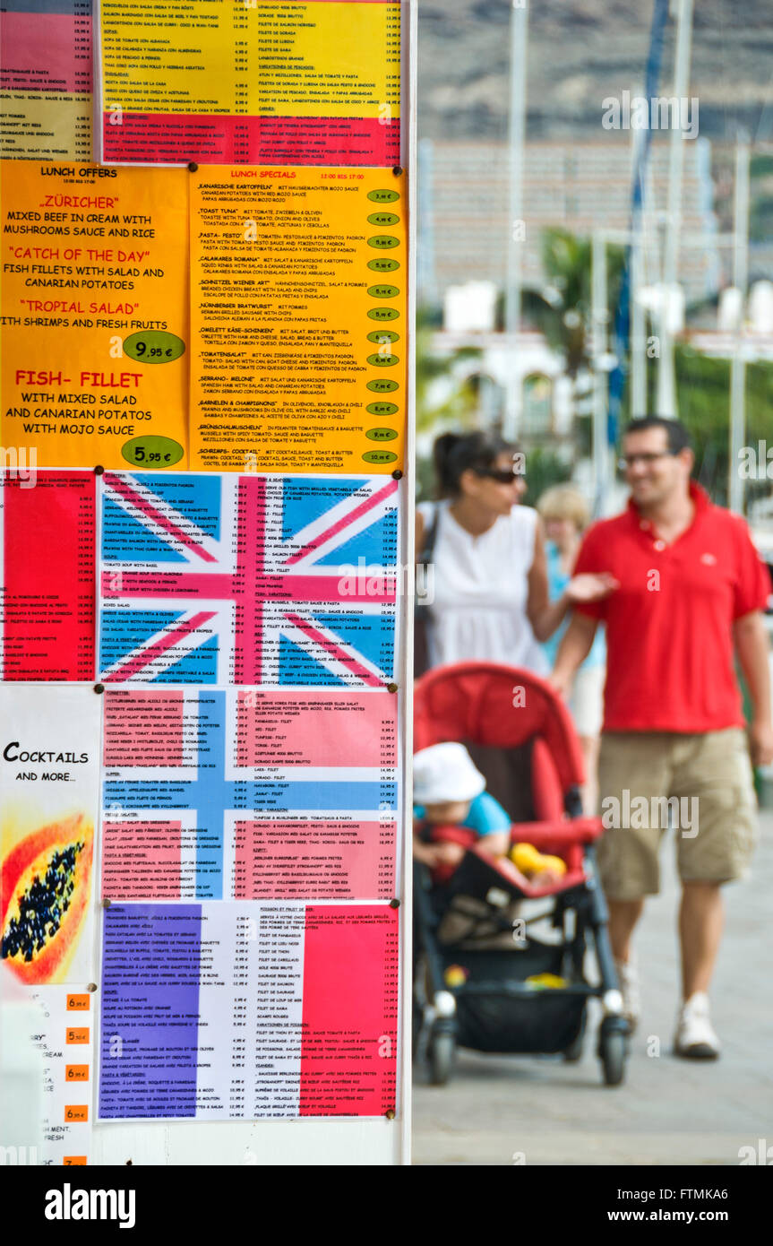 Menu multilingue scheda con le bandiere nazionali per attirare i turisti con tipico spagnolo di cibo per le vacanze con la famiglia a passeggiare dietro Foto Stock