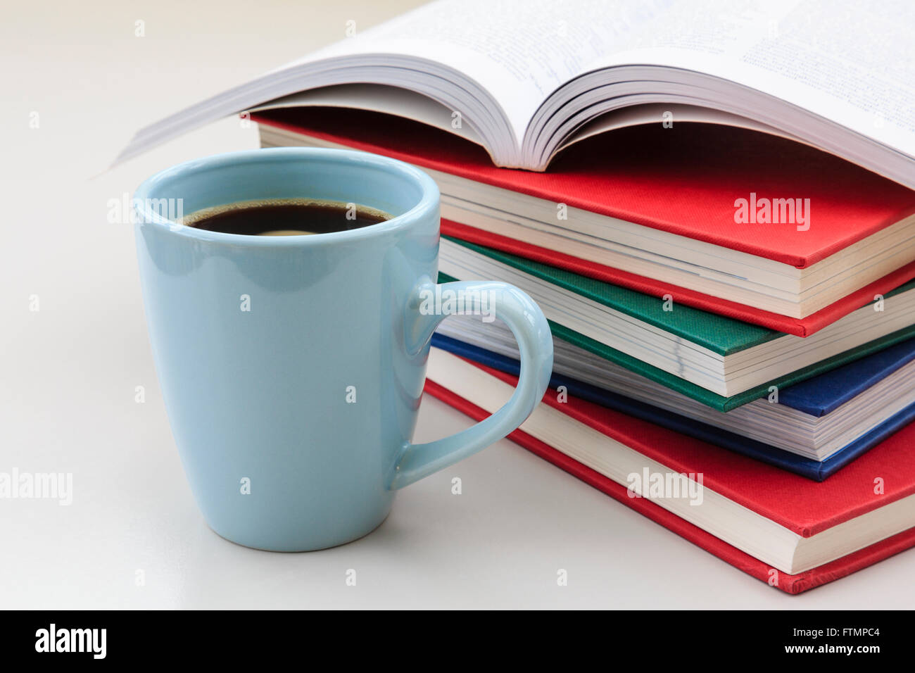 Lo studente lo studio della scena con la pila di libri su una scrivania con una tazza di forte caffè nero per aiutare a rimanere sveglio per revisione esame. Inghilterra Regno Unito Gran Bretagna Foto Stock