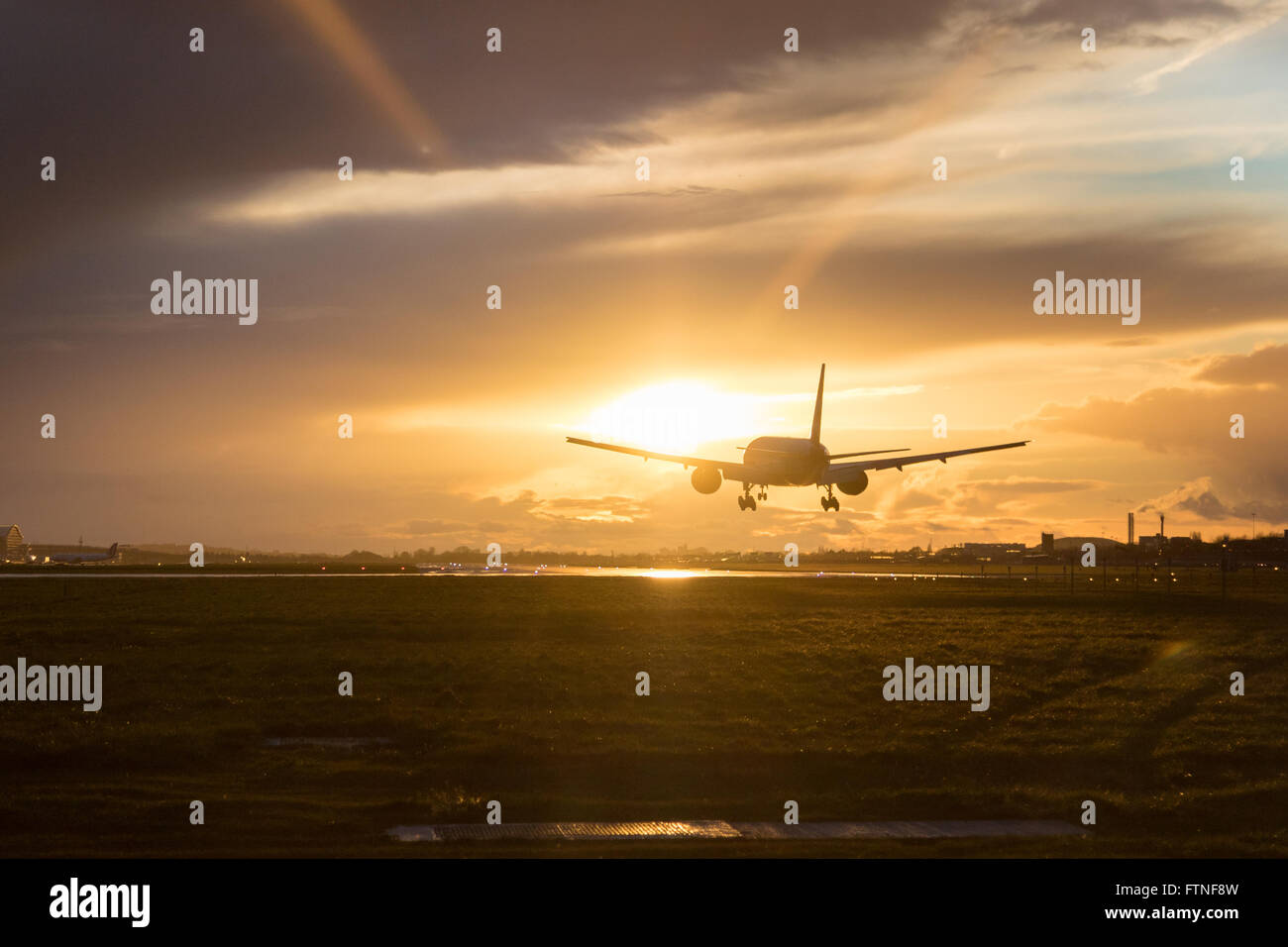 Un British Airways Boeing 777-300 atterra all'Aeroporto di Londra Heathrow come il tramonto illumina le nuvole. Foto Stock