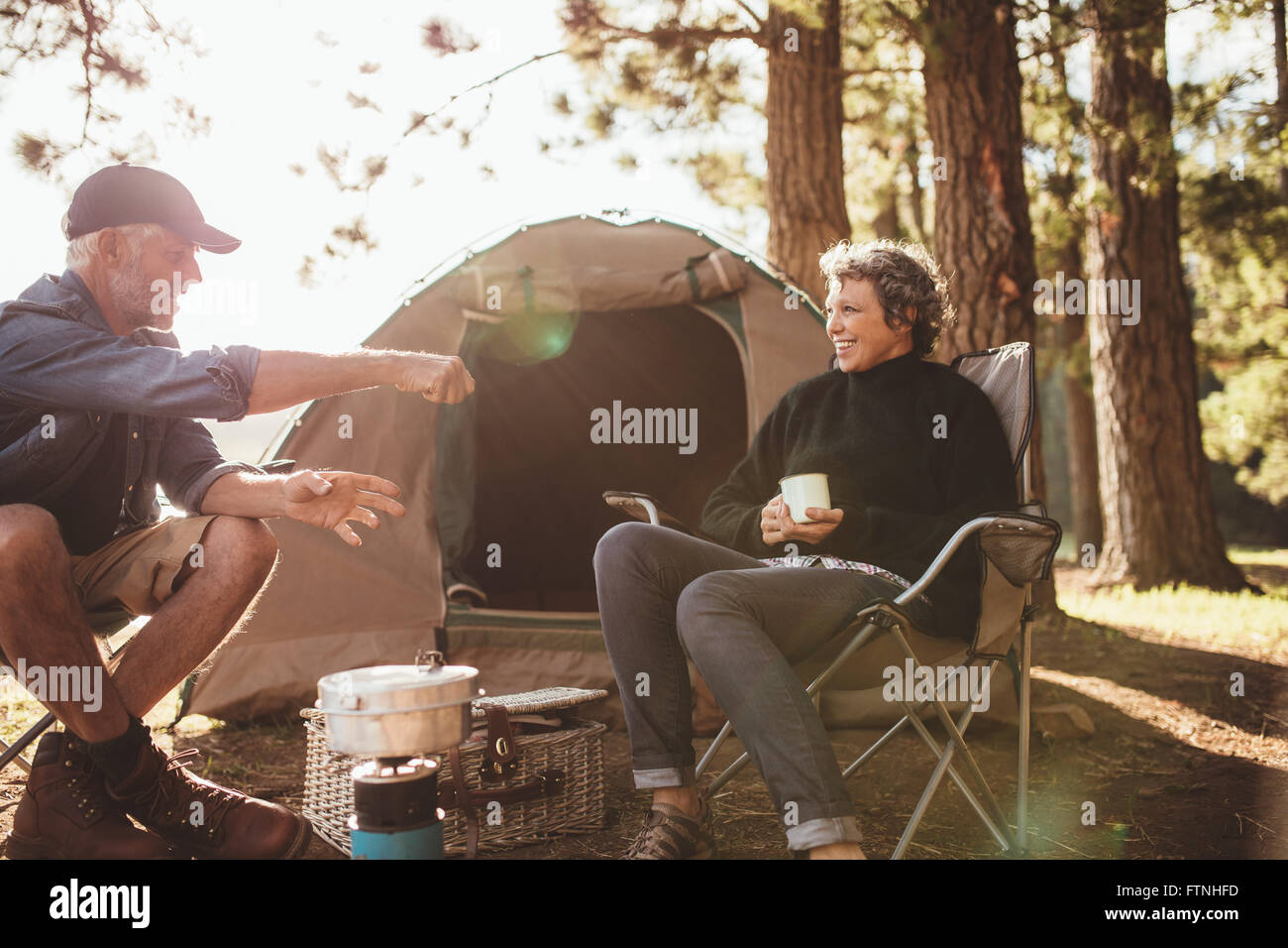 Ritratto di senior camper avente un buon tempo durante un viaggio di campeggio su un giorno d'estate. Sorridente Coppia matura seduto fuori tenda Foto Stock