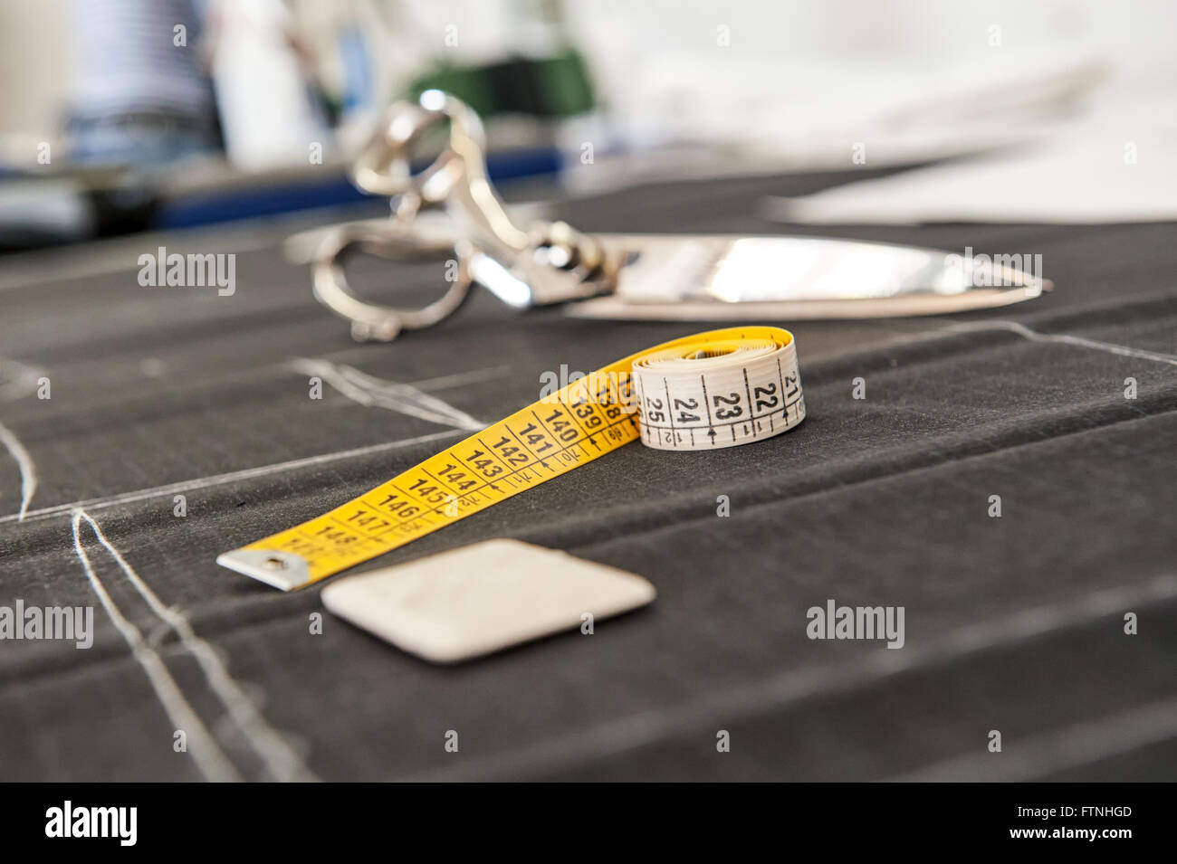 Chalk e una misura di nastro sul tessuto non tagliato in un negozio di sartoria Foto Stock