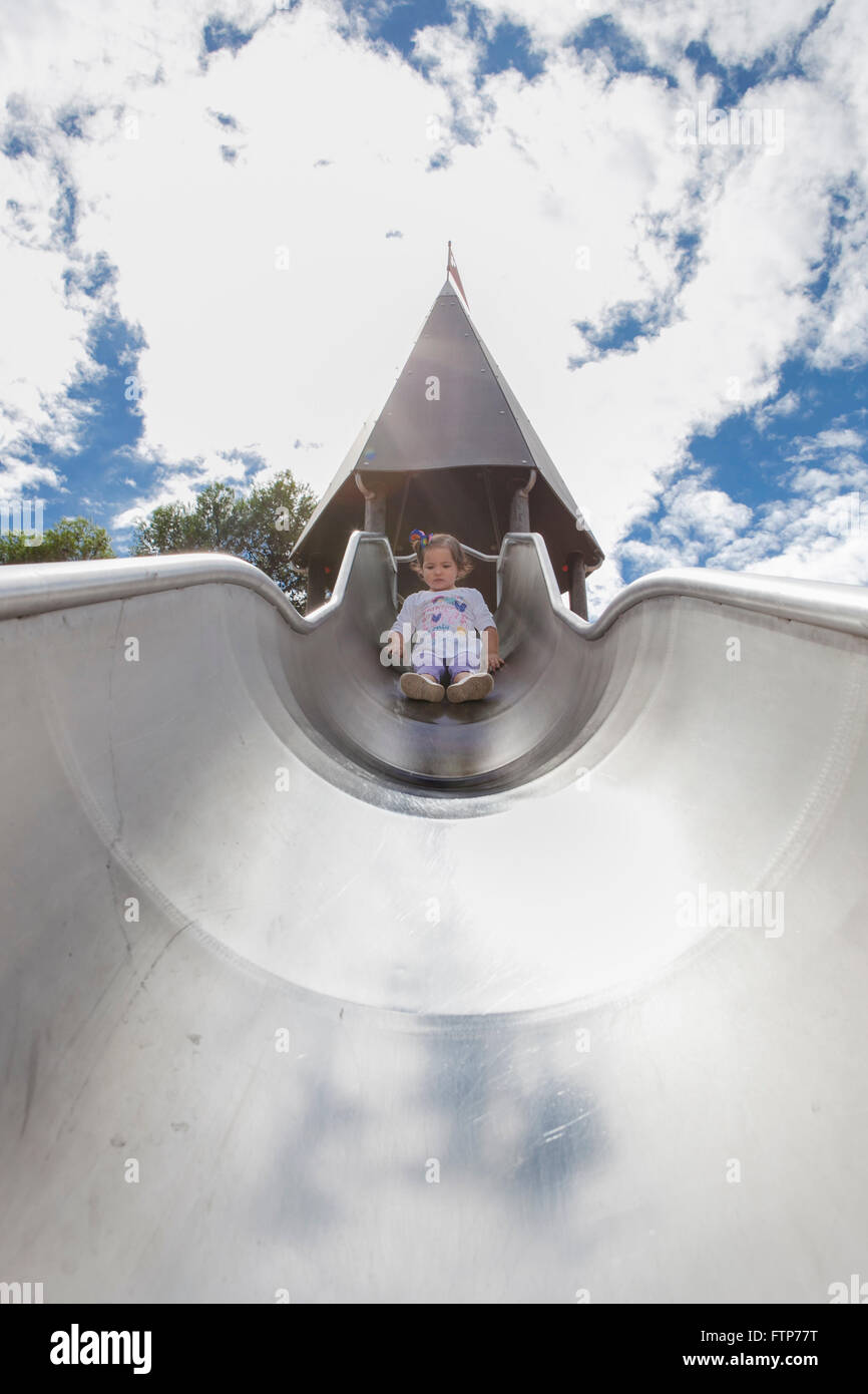 Bellissima bambina sulla sommità del parco giochi in metallo slitta Foto Stock