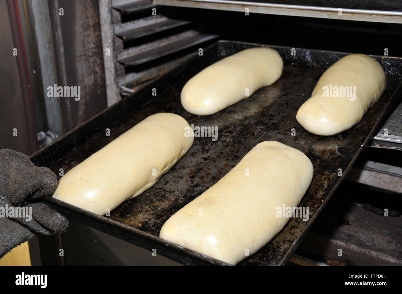 Persona di mettere il pane a cuocere in forno Foto Stock
