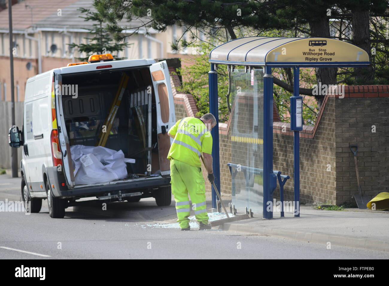Un uomo che spazia fino alla rottura di un vetro della finestra su un soggetto ad atti vandalici fermata bus a Barnsley, South Yorkshire, Regno Unito. Foto Stock