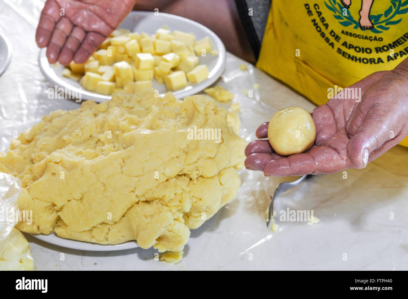 Volontari preparare gli gnocchi ripieni di formaggio manioca venduti sulla prima parte di manioca Foto Stock
