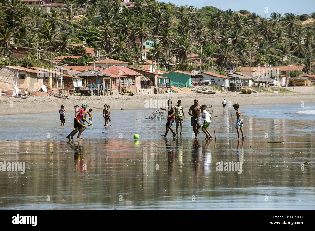 I bambini che giocano a calcio sul lungomare di Praia Redonda - villaggio di pescatori in background Foto Stock