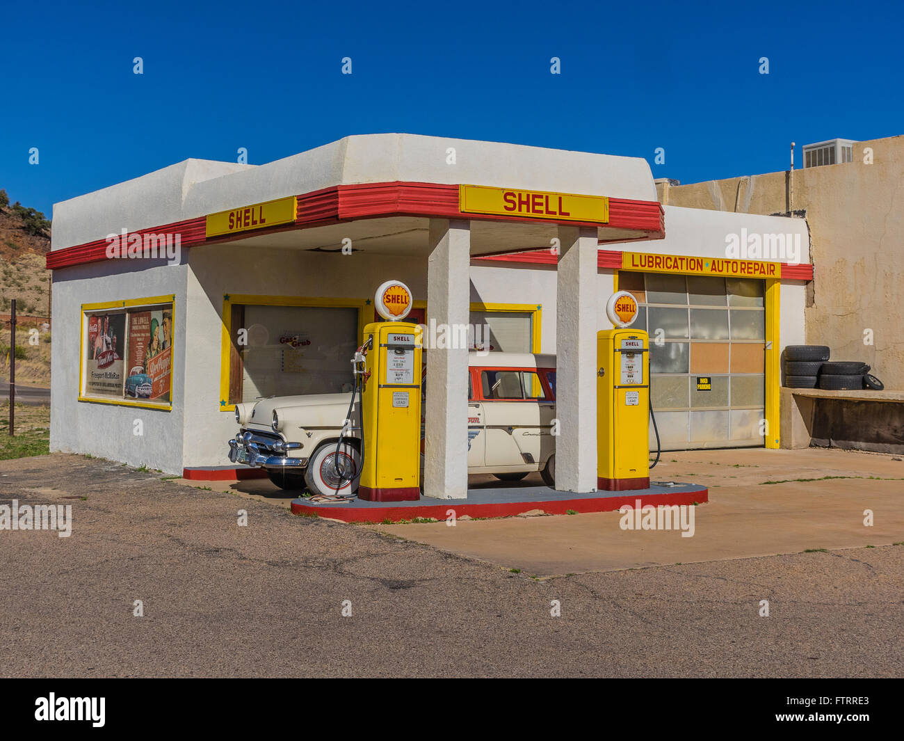 Classico 1950 Stazione di rifornimento Shell dipinte di giallo e rosso nella Shell di colori e con un 1952 Ford station wagon parcheggiata di fronte. Foto Stock
