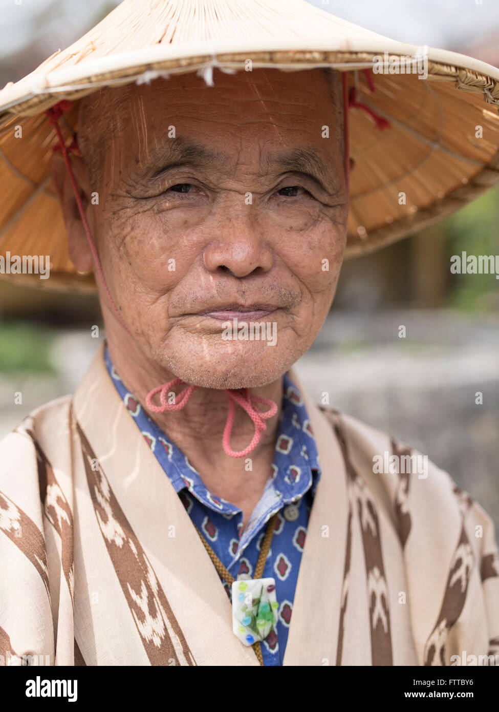 Anziani uomo di Okinawa (83) indossando il tradizionale cappello di paglia e semplice yukata a Okinawa Mondo, Okinawa, in Giappone. Foto Stock