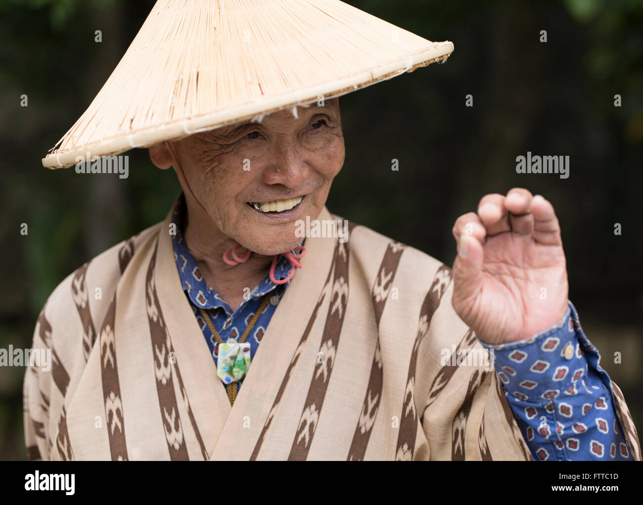 Anziani uomo di Okinawa (83) indossando il tradizionale cappello di paglia e semplice yukata a Okinawa Mondo, Okinawa, in Giappone. Foto Stock