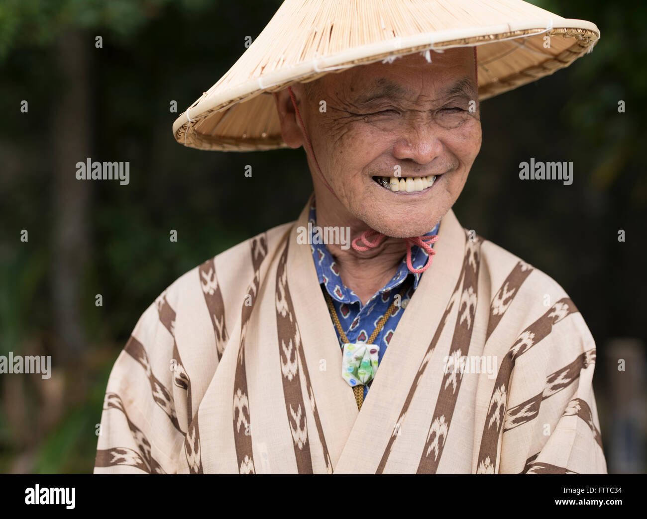 Anziani uomo di Okinawa (83) indossando il tradizionale cappello di paglia e semplice yukata a Okinawa Mondo, Okinawa, in Giappone. Foto Stock