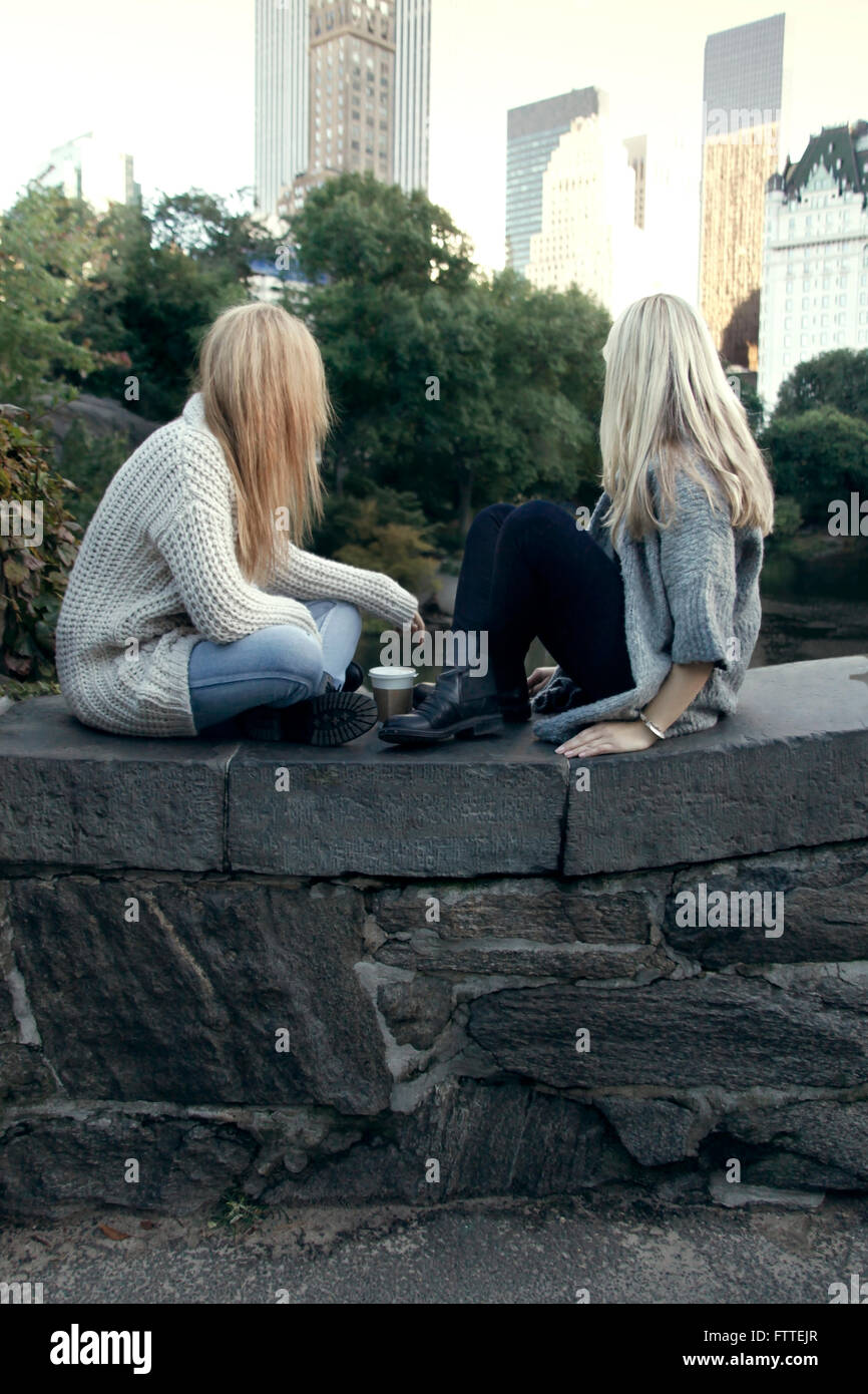 Due giovani donne sedute in Central Park in autunno Foto Stock