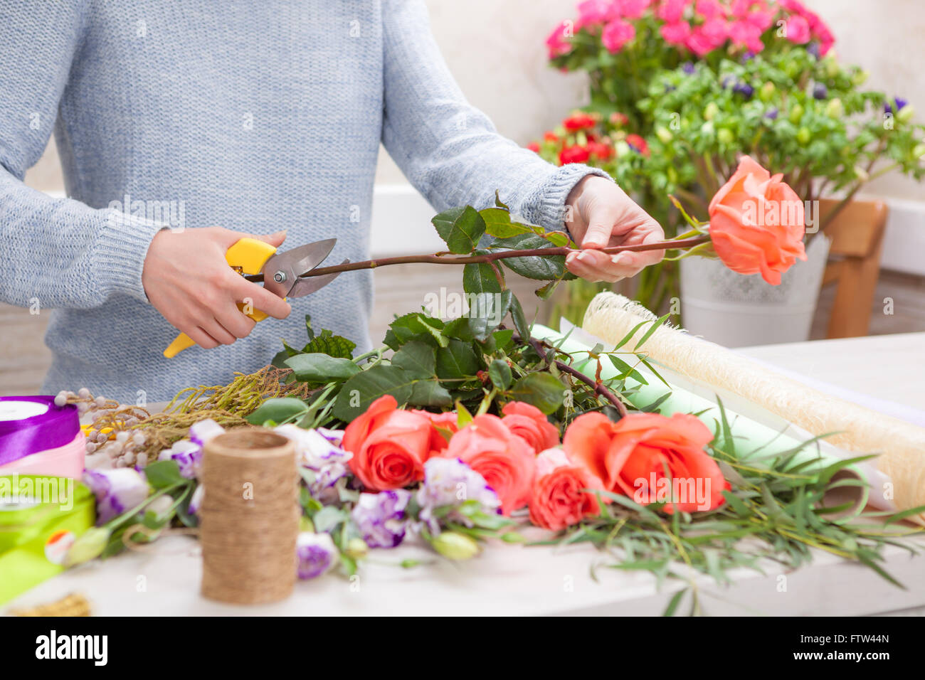 Fioraio al lavoro. Mani femminili la potatura di rose nel negozio di fiori. Foto Stock