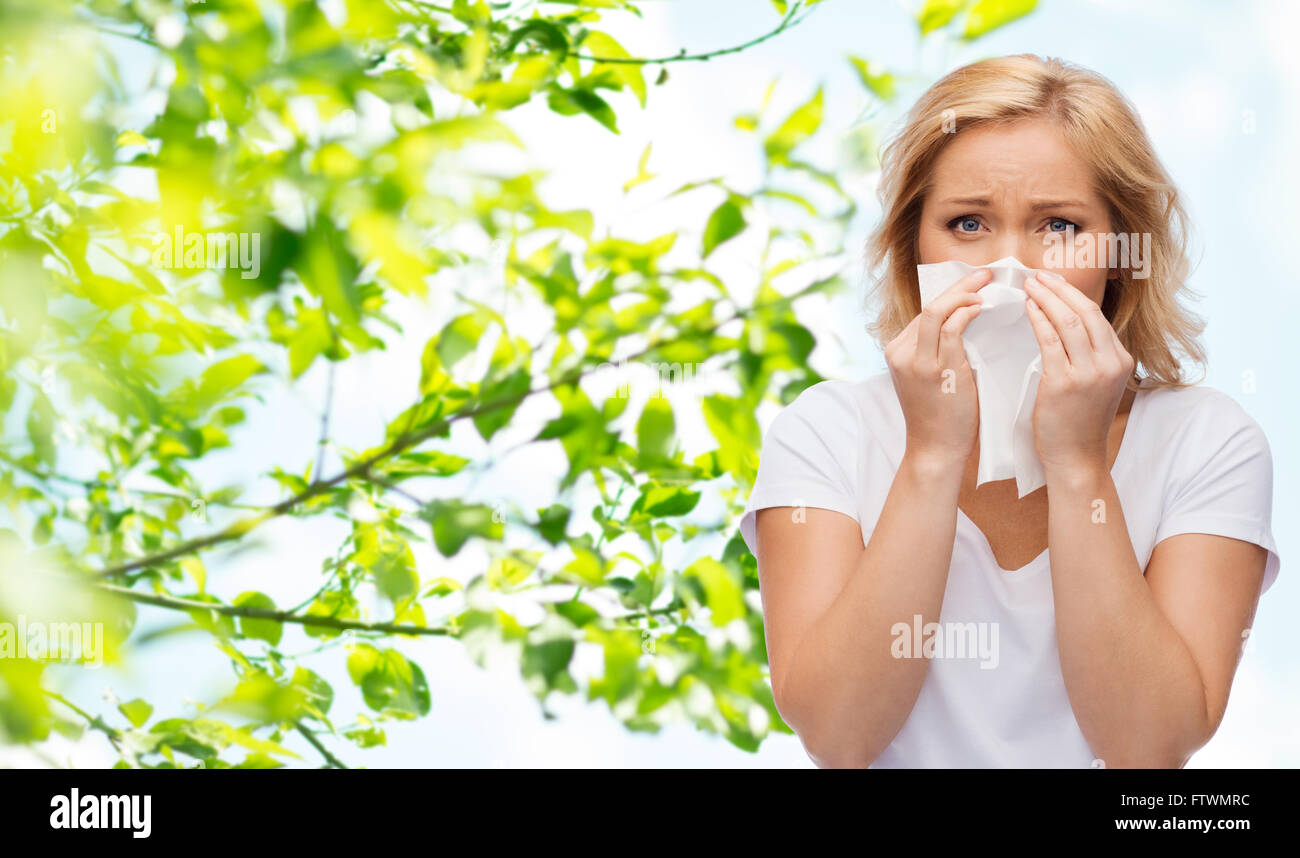 Donna infelice con il tovagliolo di carta soffia il naso Foto Stock
