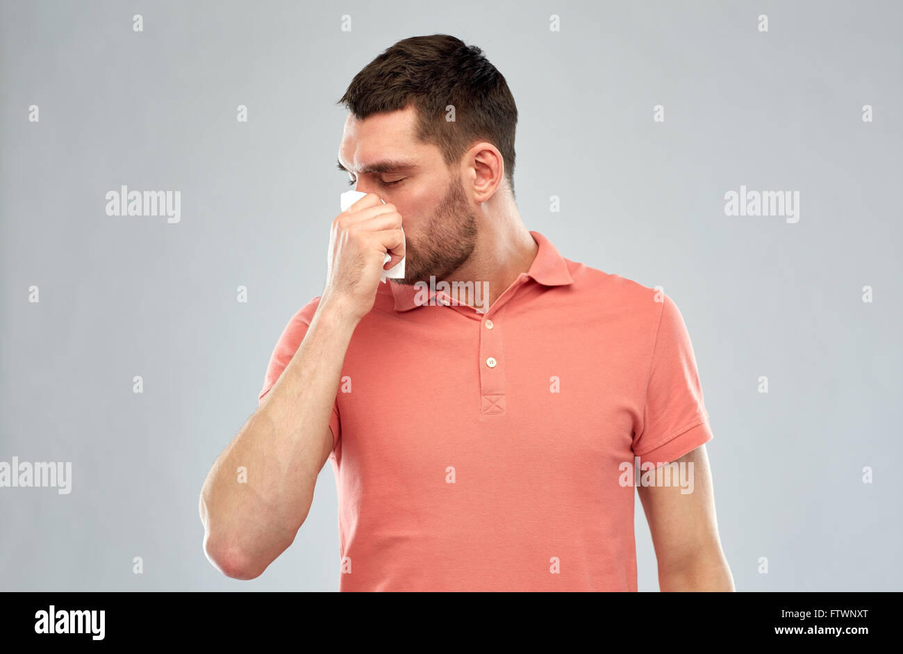 Uomo malato con della carta assorbente soffia il naso Foto Stock