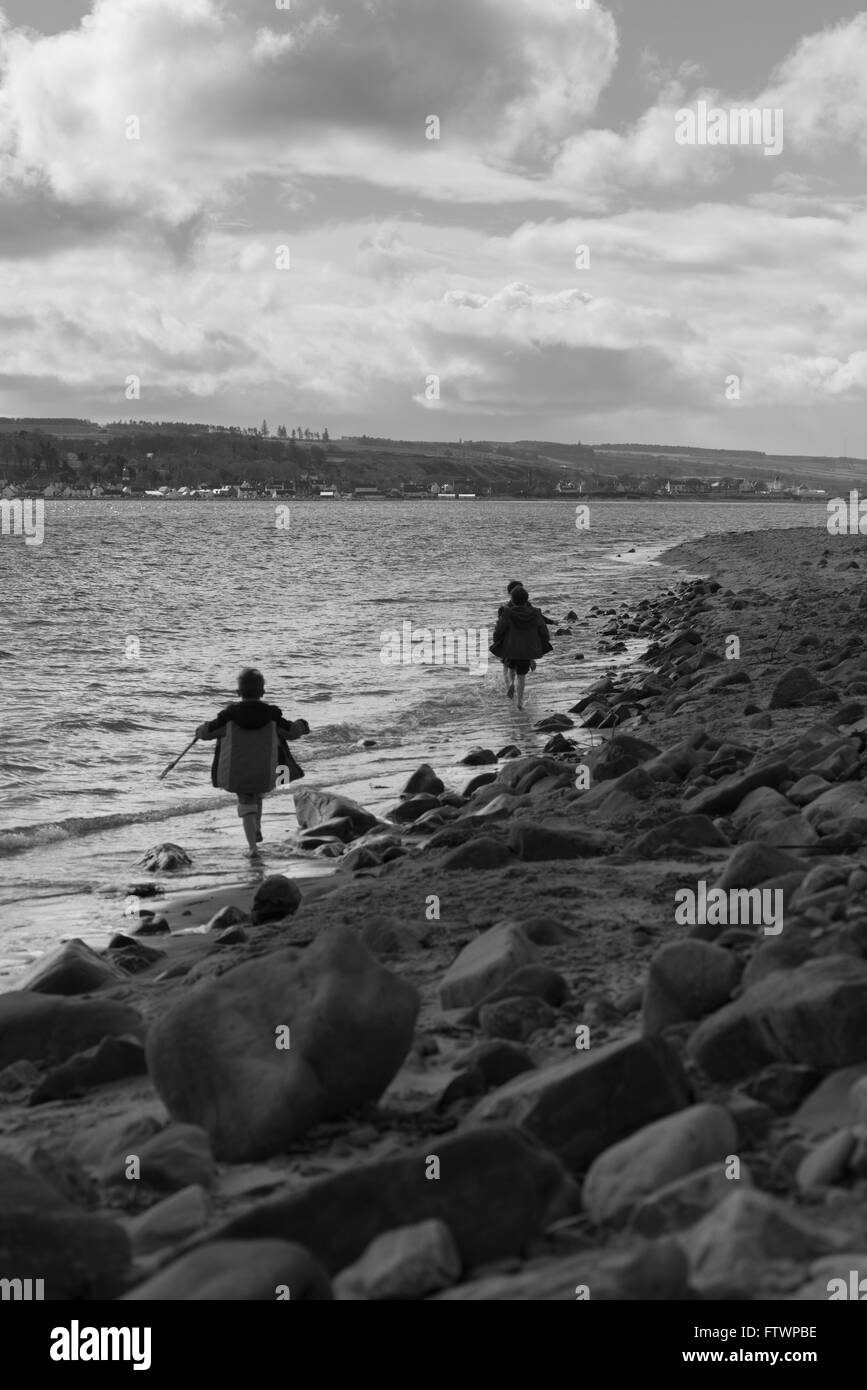 Ragazzi giocando sulla spiaggia rocciosa vicino nigg highlands scozzesi Foto Stock