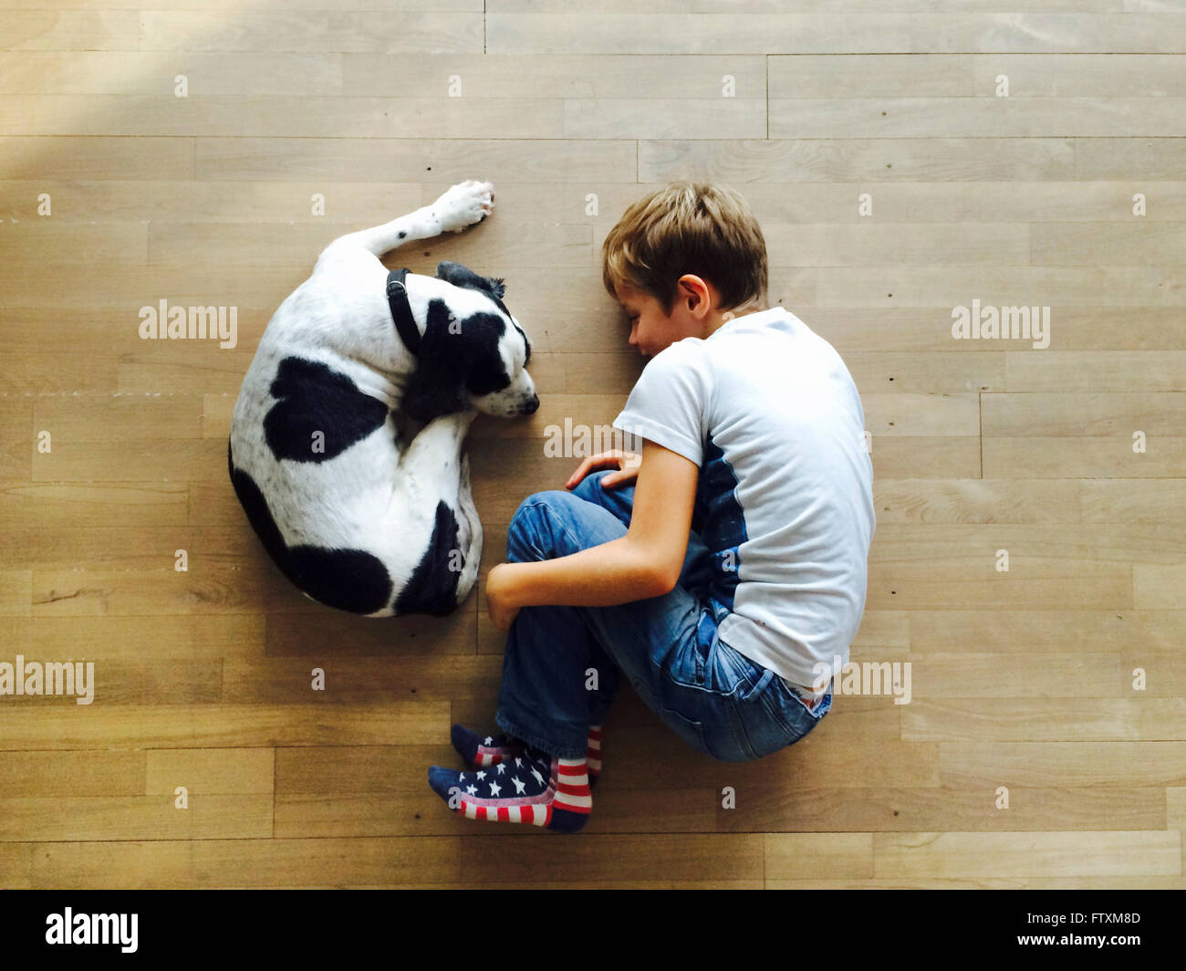 Un ragazzo e il suo cane rannicchiato sul pavimento Foto Stock