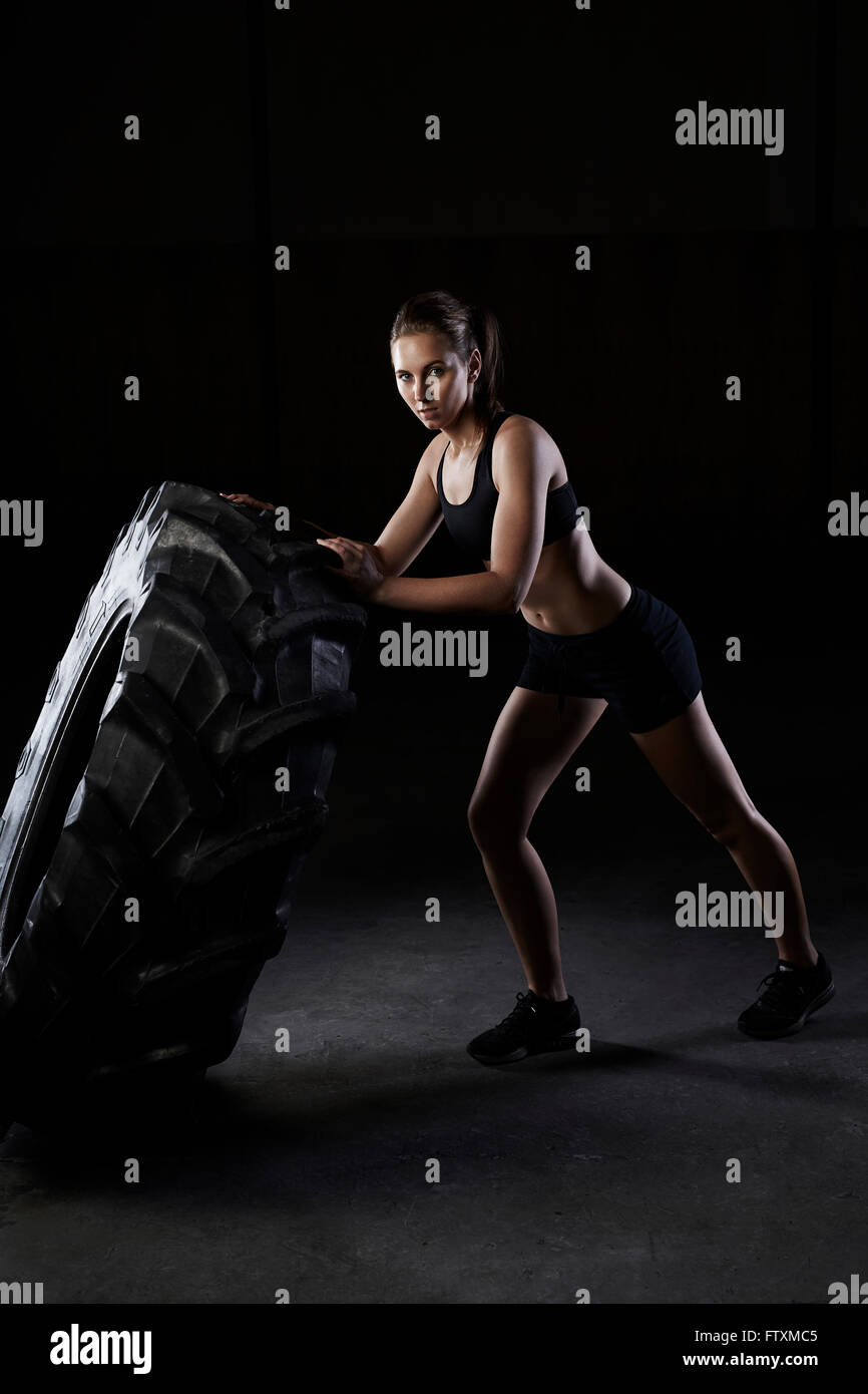 Giovane donna spingendo un carrello pneumatico in palestra Foto Stock